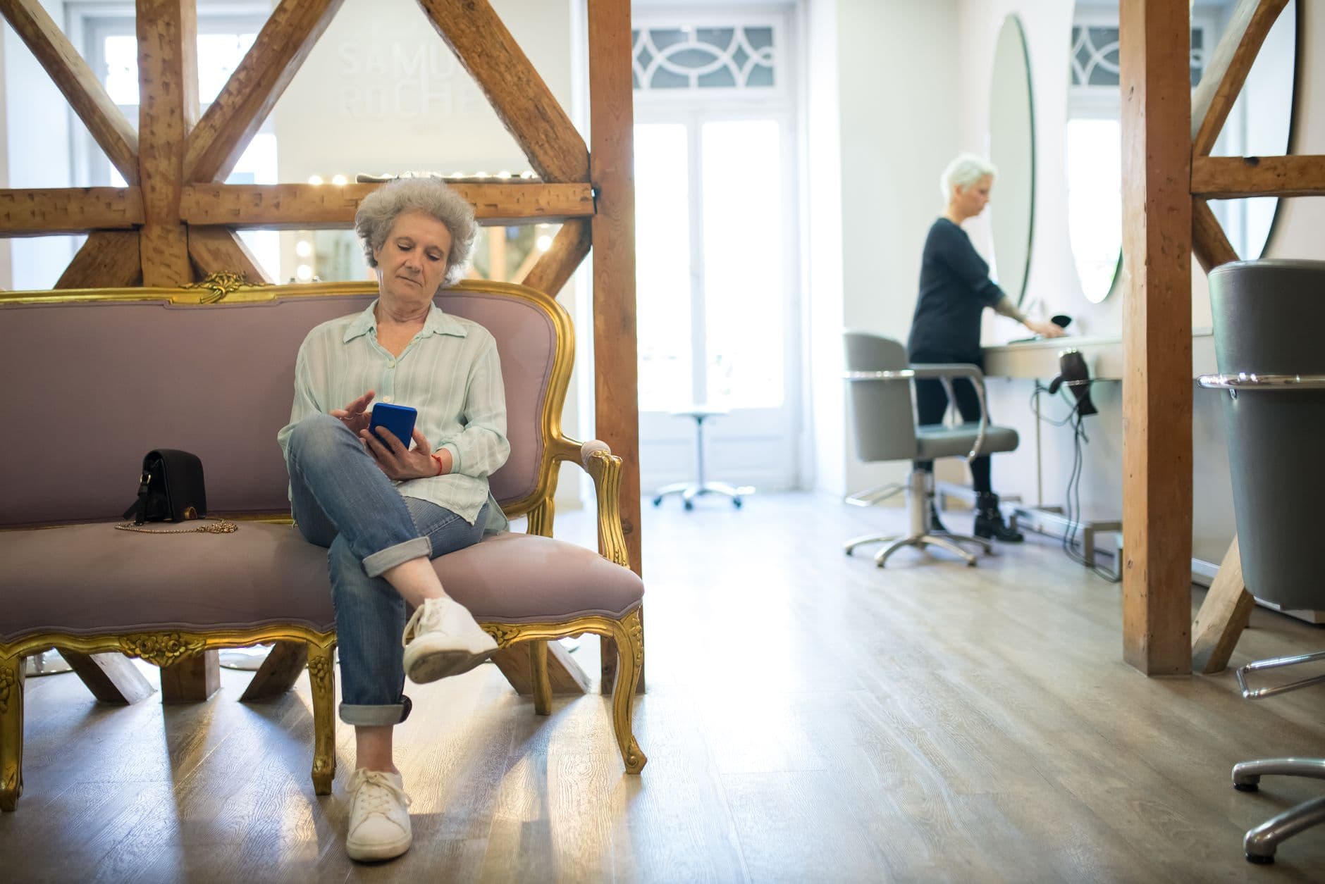 Clienta usando el móvil sentada en un salón de belleza